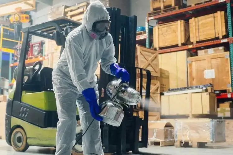 Person hält Sprühgerät in Industriehalle.
